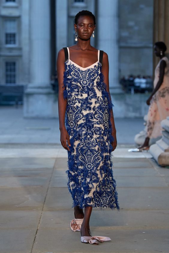 woman on runway wearing blue and white patterned and feathered maxi dress