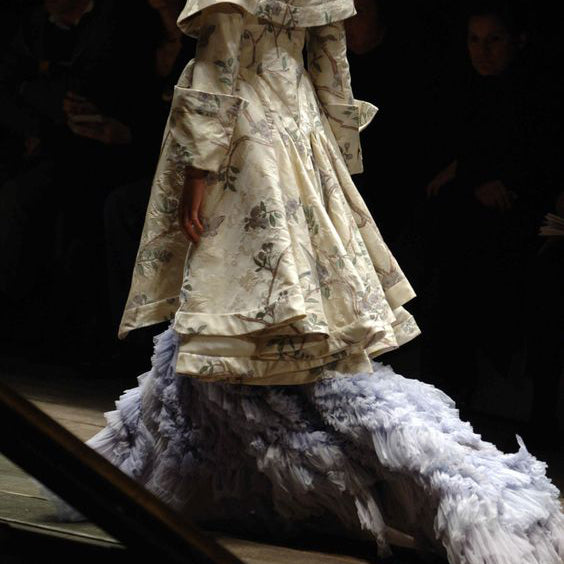 a fashion show runway model wearing a frilly dress and coat, romantic victorian inspired but edgy