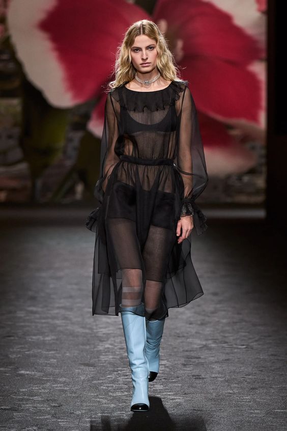 woman on runway wearing black tulle dress and blue boots