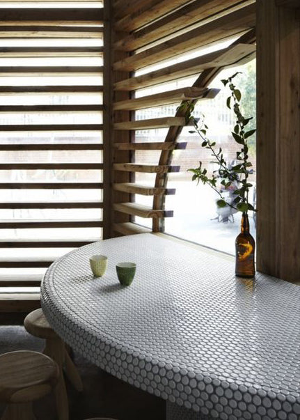 A round half table covered in penny round tiles.