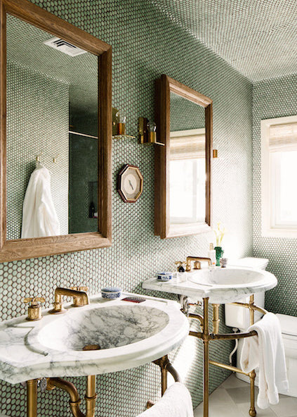 A bathroom with marble sinks and green penny rounds on the wall and ceiling.