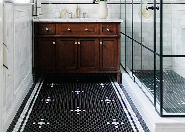 A bathroom with a black and white penny round floor and shower floor.