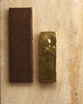 Two glazed terracotta tiles against a tan background, one brown and one gold.