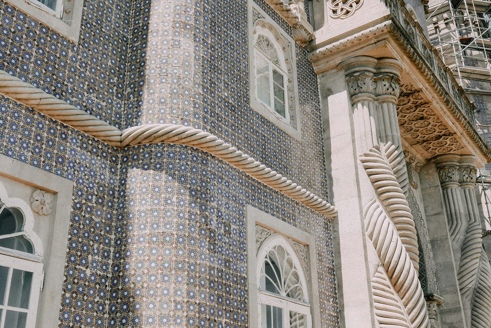 An azulejo facade in blue and yellow, with twisted looking columns that twist around each other again..