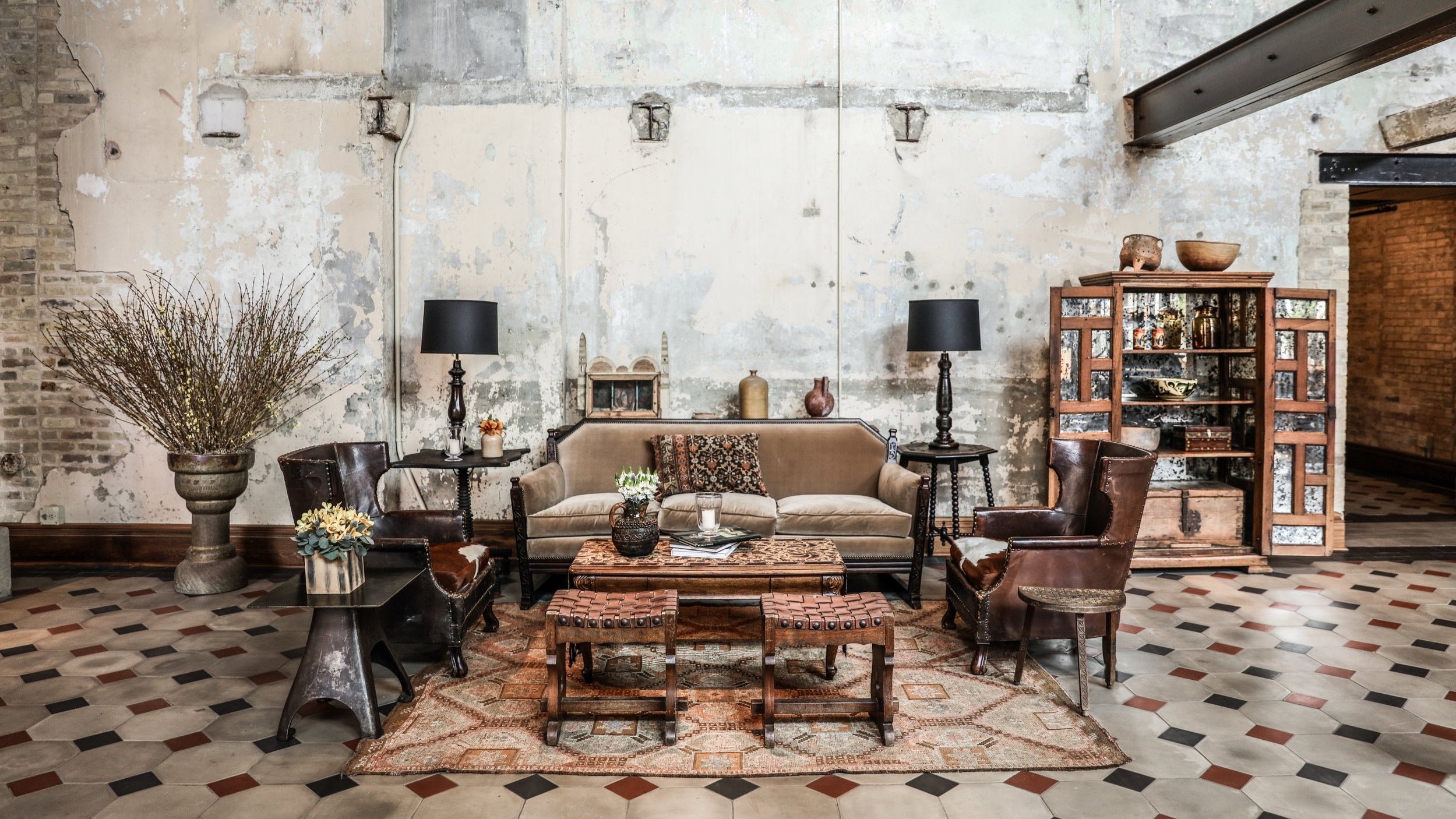 A hotel lobby sitting area with artfully unfinished walls and steel beams and a cement tile floor.