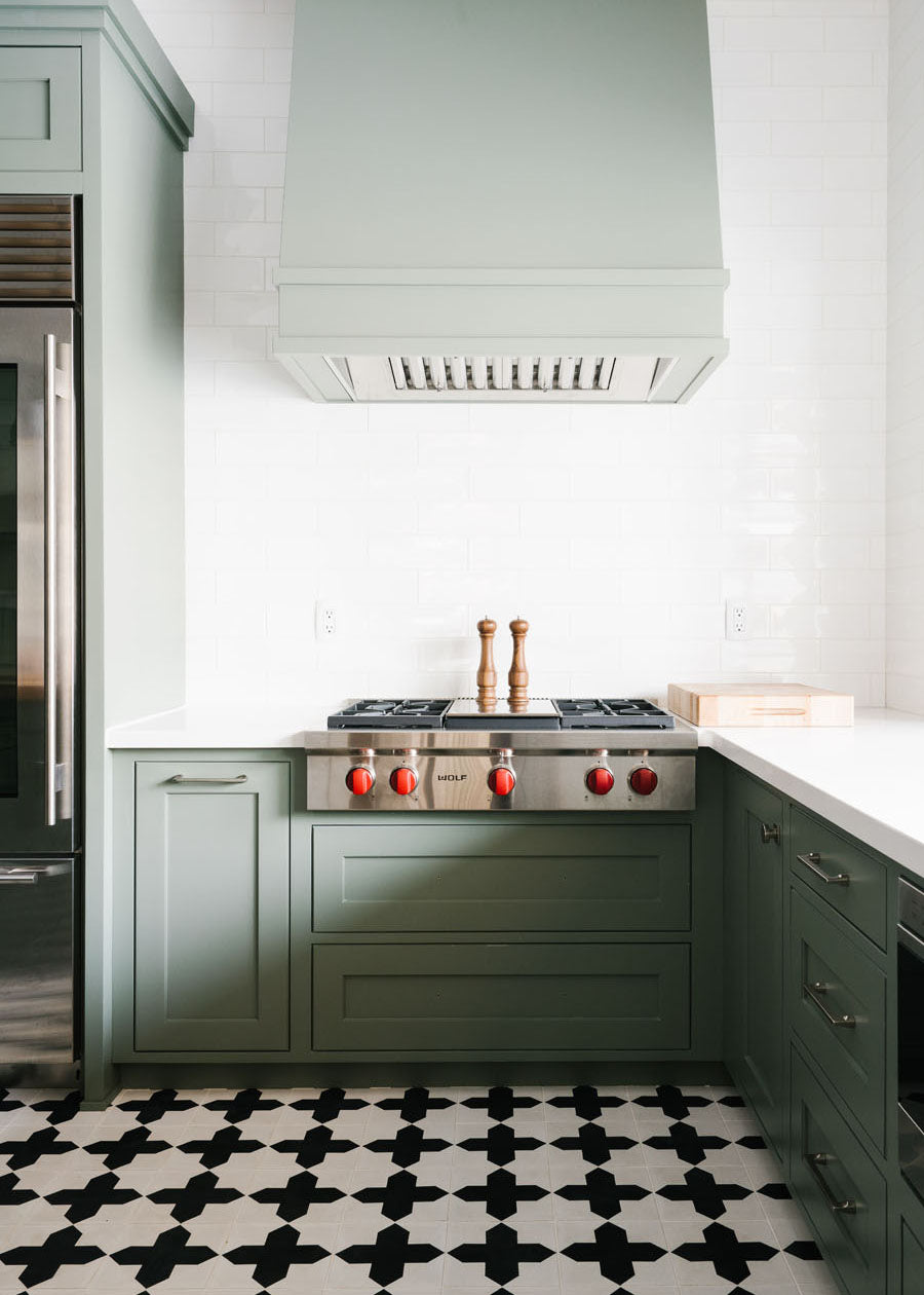 A bright kitchen with a Wolf range and black and white clé cement tile floor.