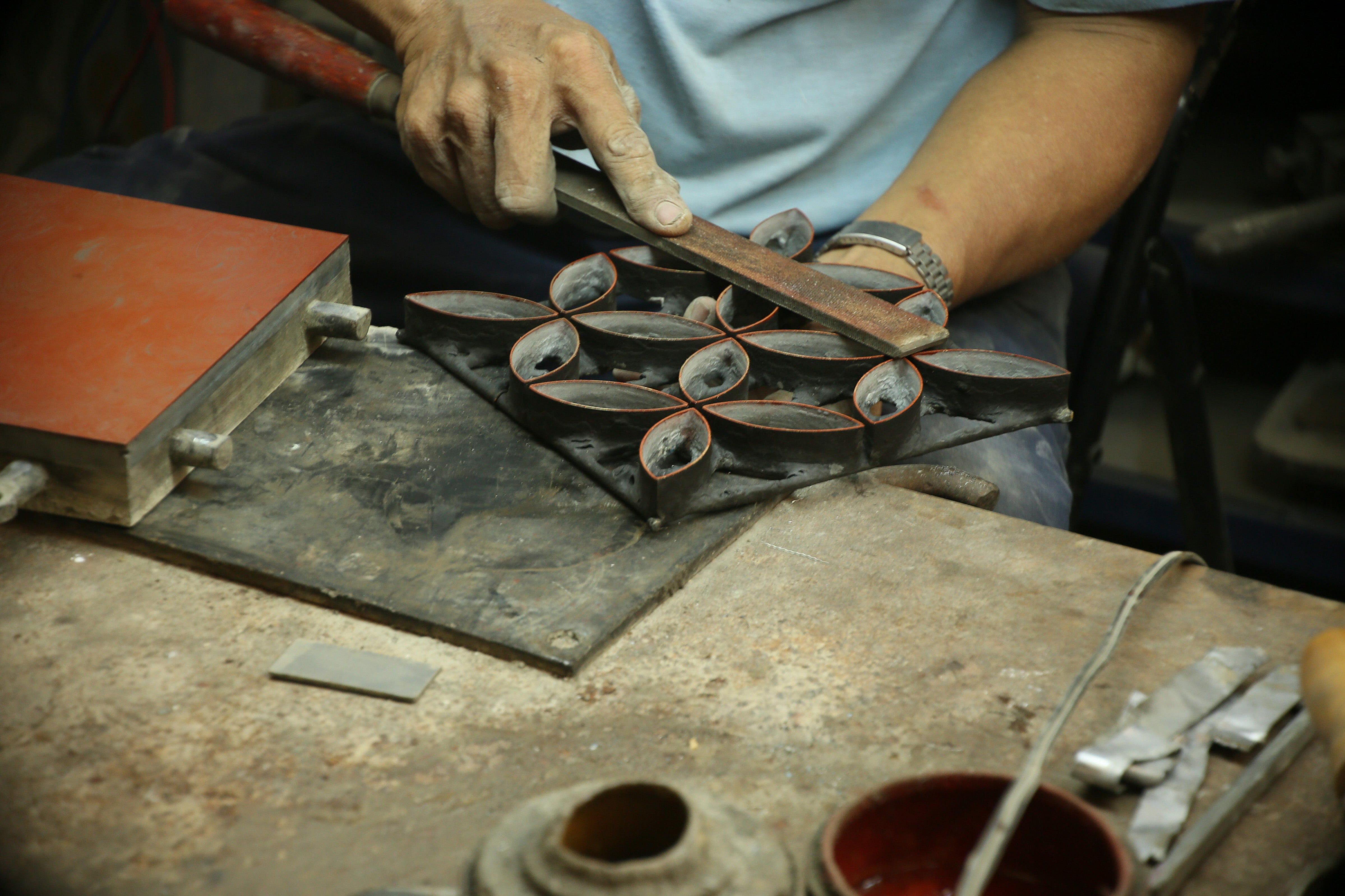 An artisan holds a mold and tools for tile making
