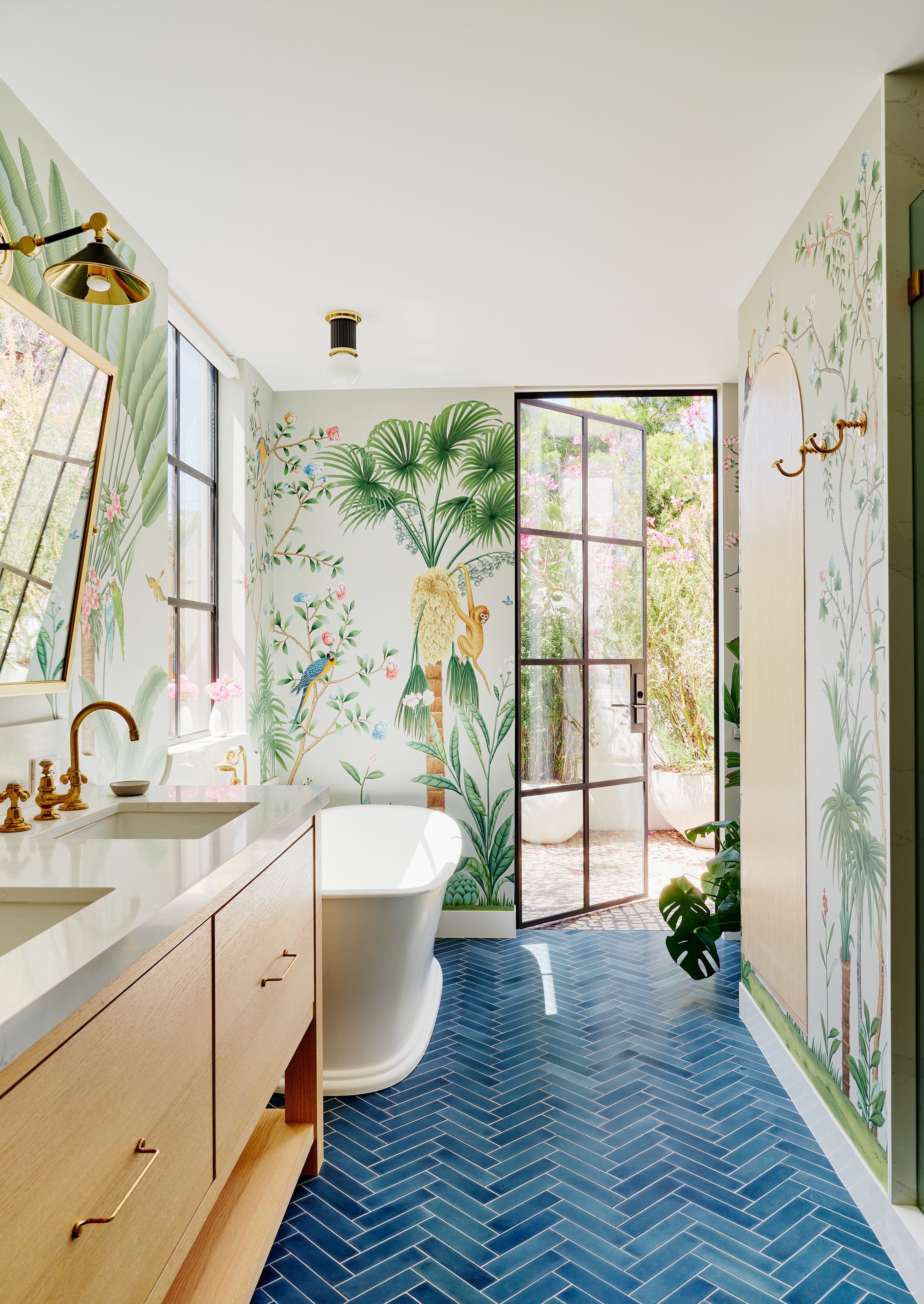 A bathroom with a wall mural of a jungle and blue rectangular clé tiles.