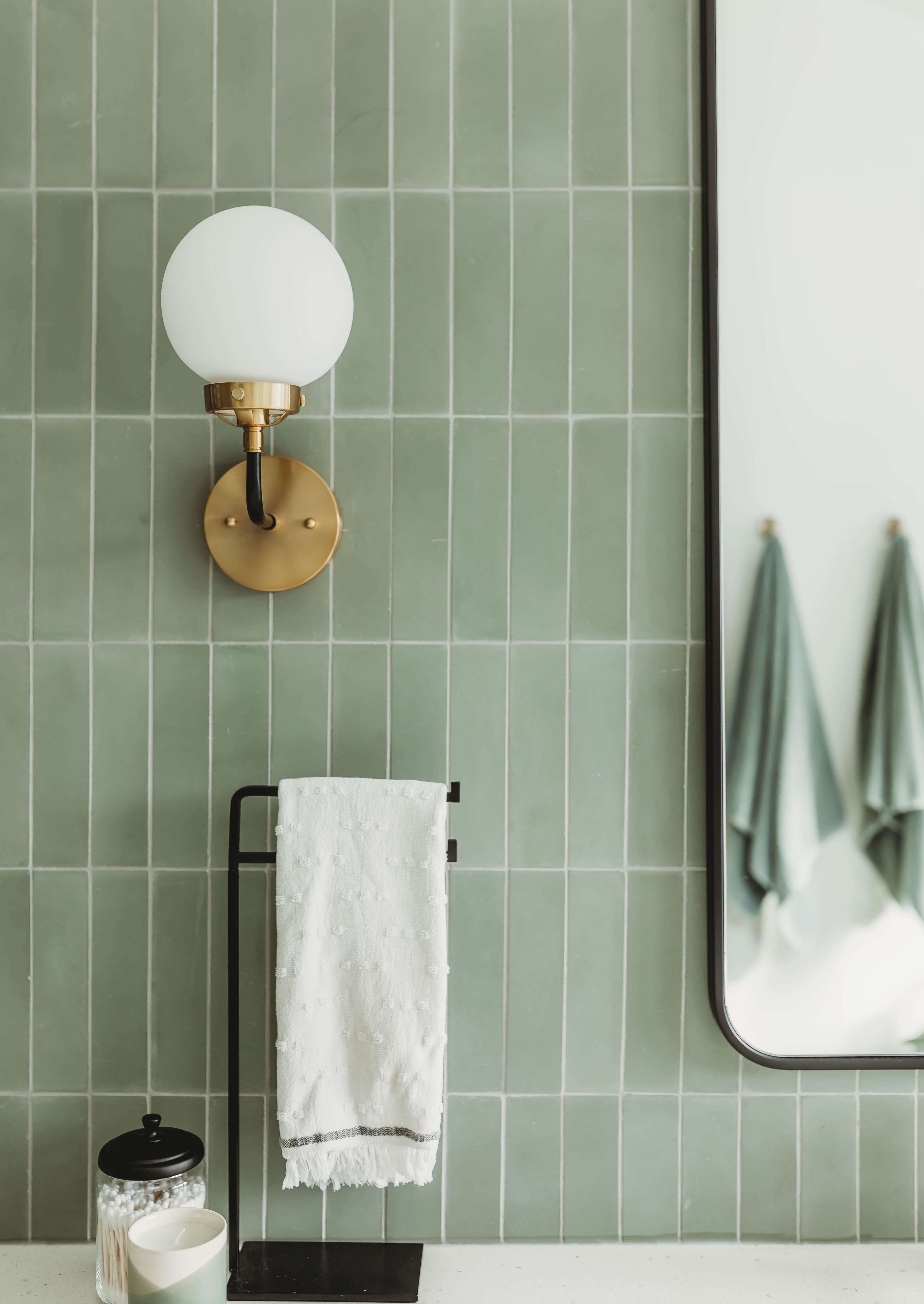 Rectangular tiles in a light basil green, installed vertically on a bathroom wall.