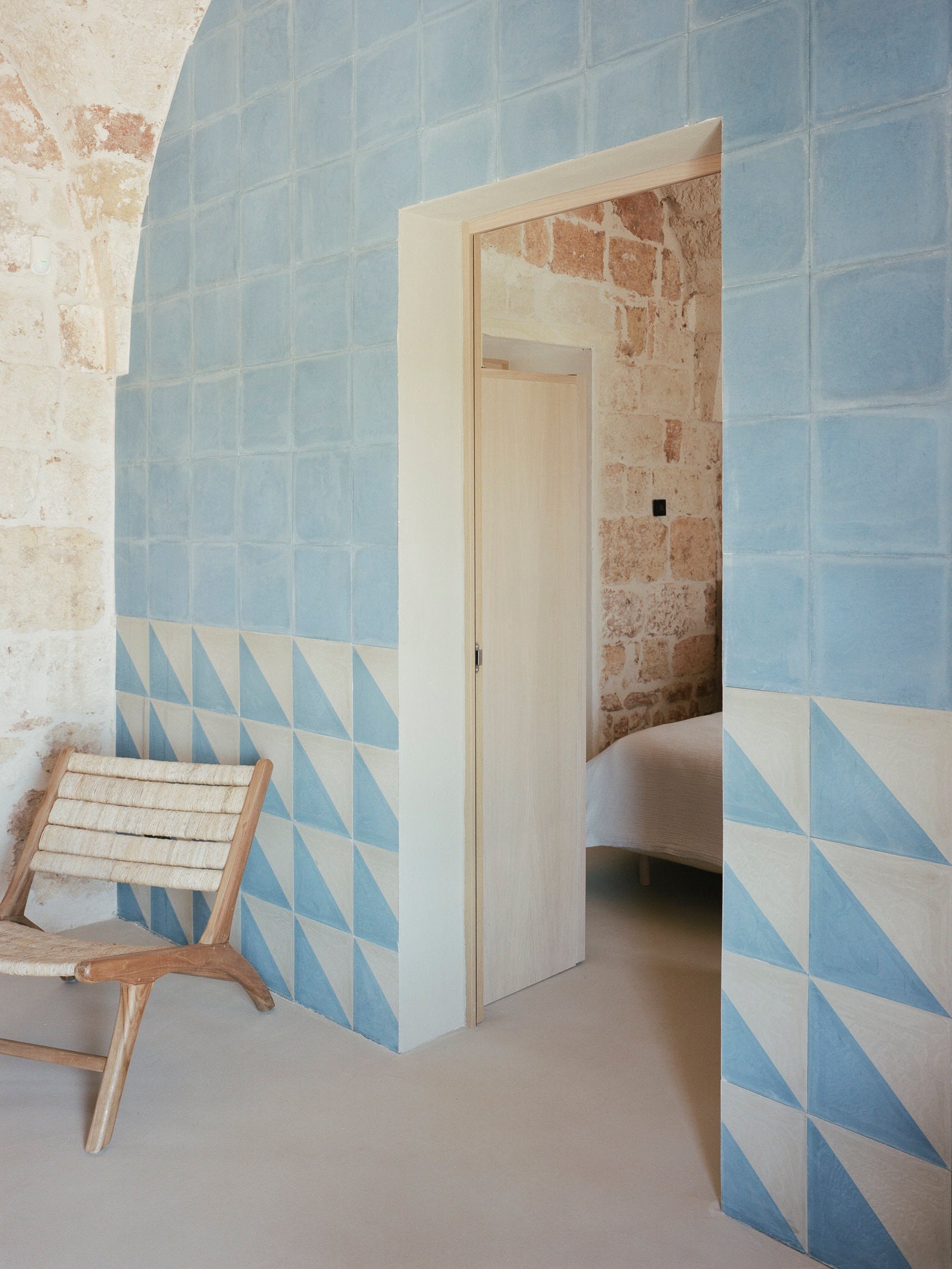 Faded light blue tile on an arched wall contrasting beige walls in Italy.