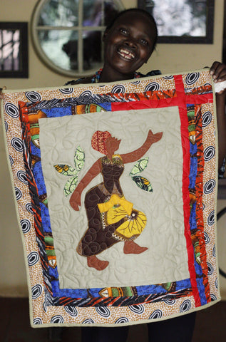 Maggie holding a wall hanging of a dancing woman