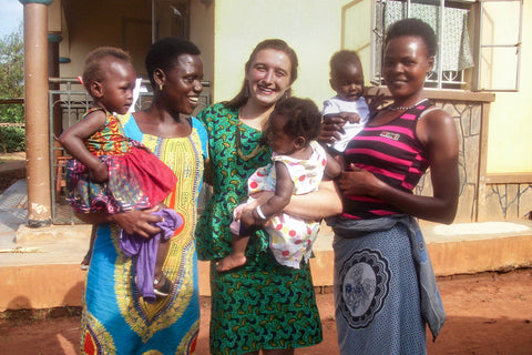 Amani intern with seamstresses holding children at amani uganda