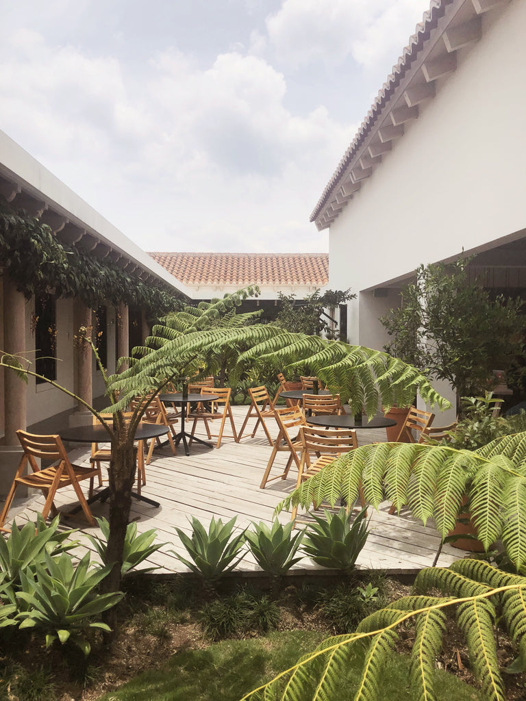 Wood outdoor patio at The Good Hotel filled with tables and chairs and surrounded by plants, best places to stay in Guatemala, best places to stay in Antigua, top antigua hotels, where should I go in Guatemala