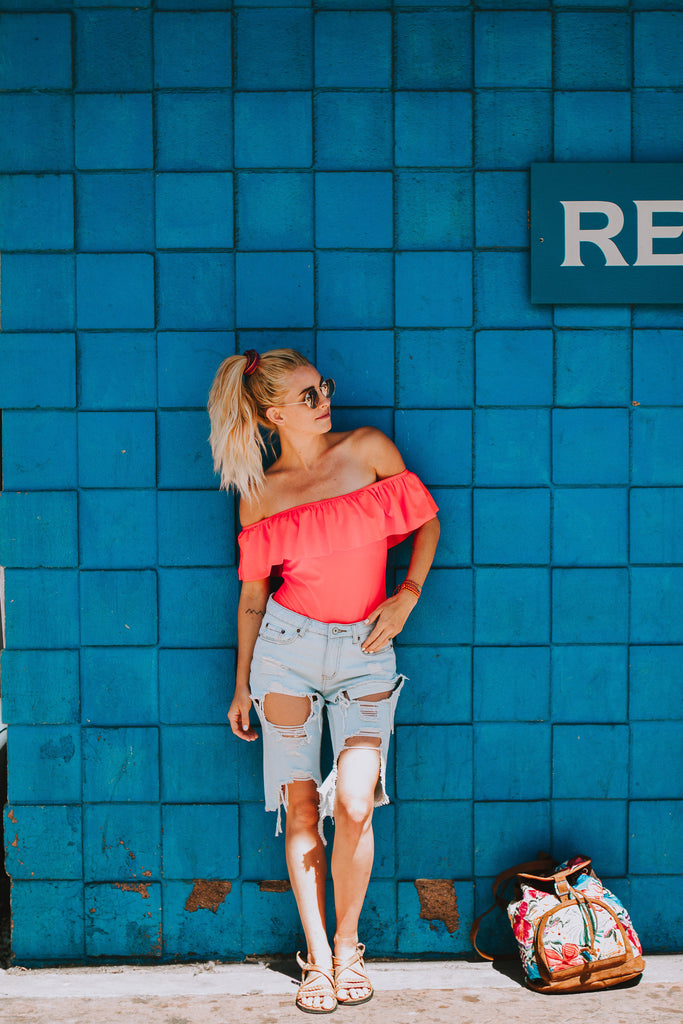 Alyssa wearing a ruffled pink swimsuit in Free People sunglasses and denim cutoffs