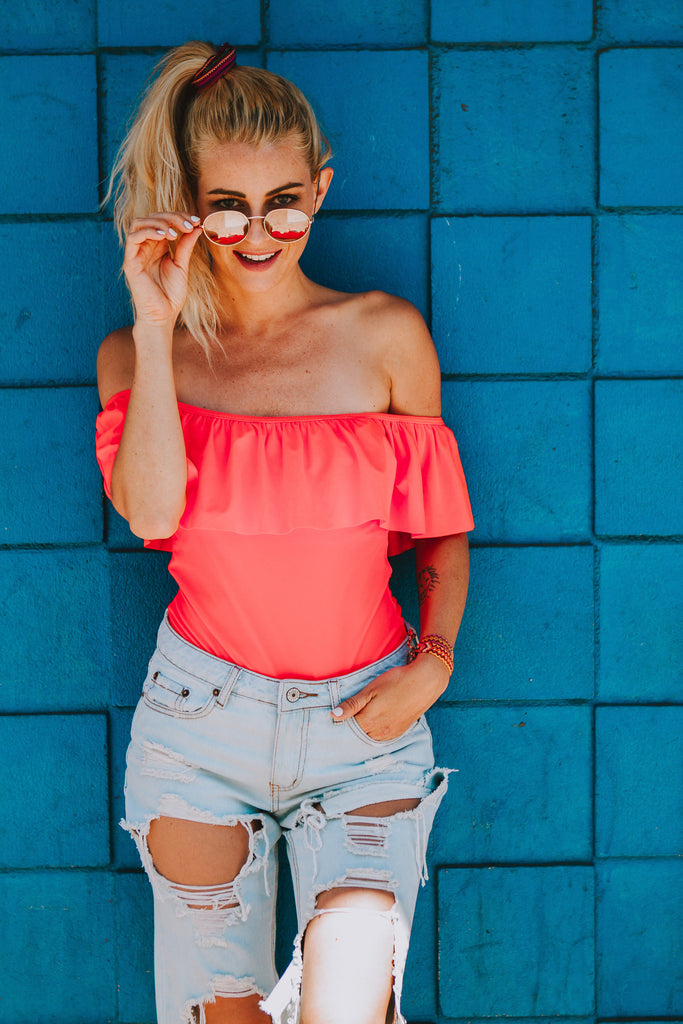 Alyssa wearing a ruffled pink swimsuit in Free People sunglasses and denim cutoffs