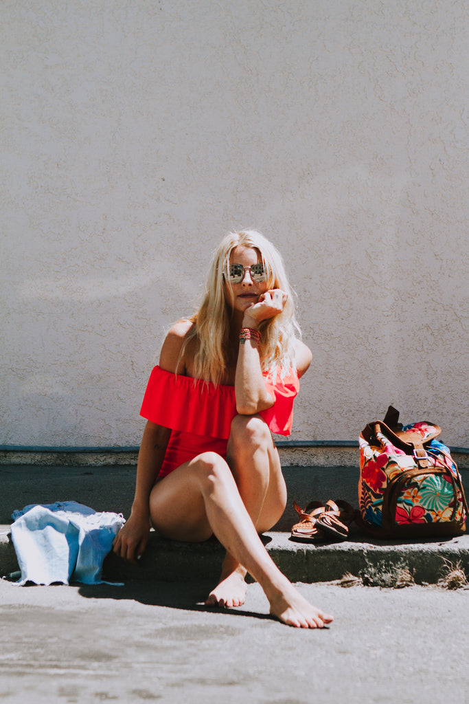 Alyssa wearing a ruffled pink swimsuit in Free People sunglasses and denim cutoffs