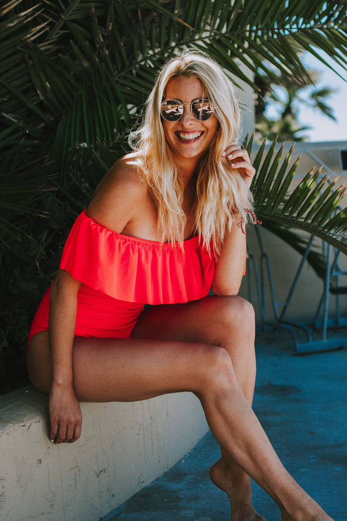 Alyssa wearing a ruffled pink swimsuit in Free People sunglasses and denim cutoffs