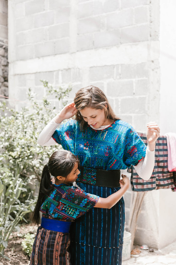 Artisan partner Rosa's daughter helps She Is Not Lost blogger Carina Otero into traditional dress, Guatemala travel, visit Lake Atitlan, life on Lake Atitlan, best places to visit in Guatemala, what to do in Guatemala