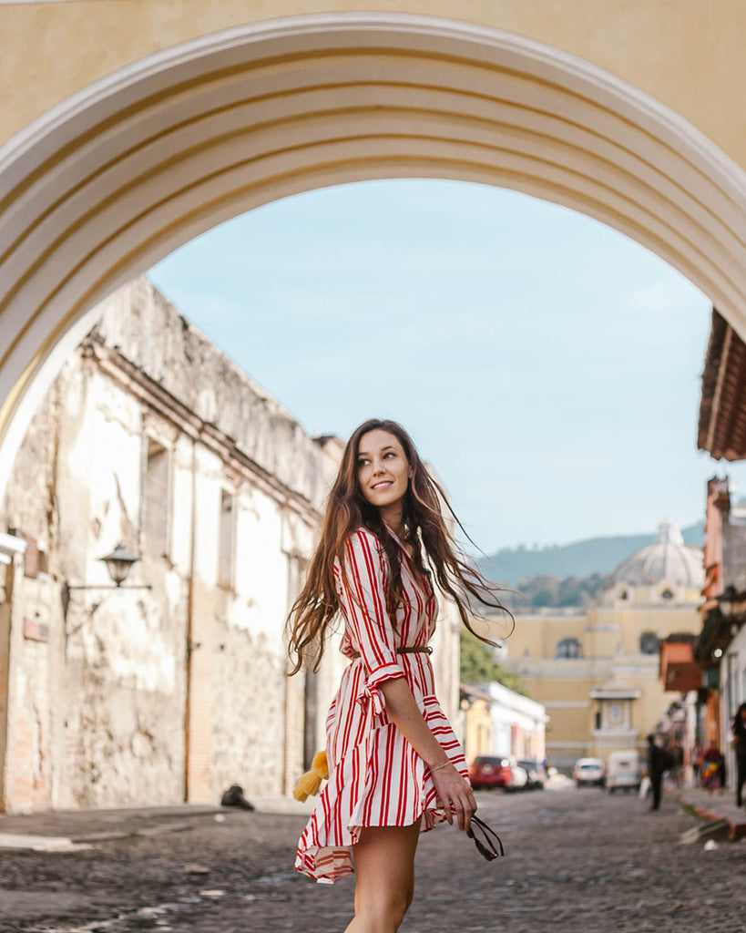 She Is Not Lost blogger Carina Otero wearing red and white striped dress posing in Antigua with Hiptipico bag, Antigua ethical travel, ethical travel programs in Latin America, how to travel ethically in Guatemala