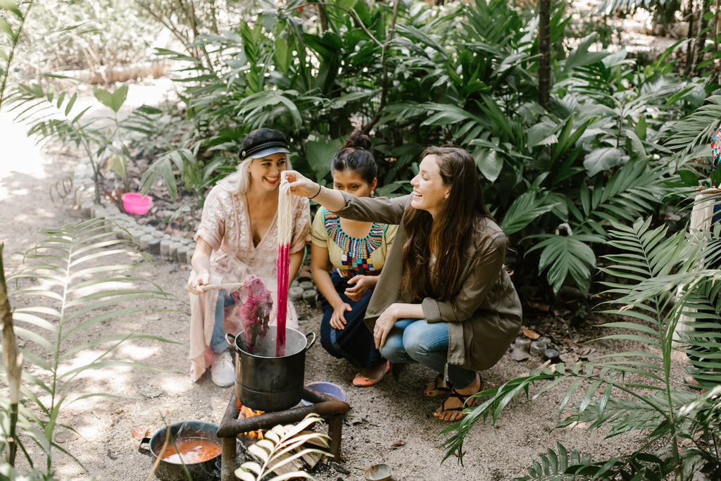 Alyssa and Carina laugh with artisan partner as the fabric is pulled out from the pot as a vibrant pink, natural dyeing workshops, where to learn to weave in Lake Atitlan, what to do in Guatemala, must visit Guatemala