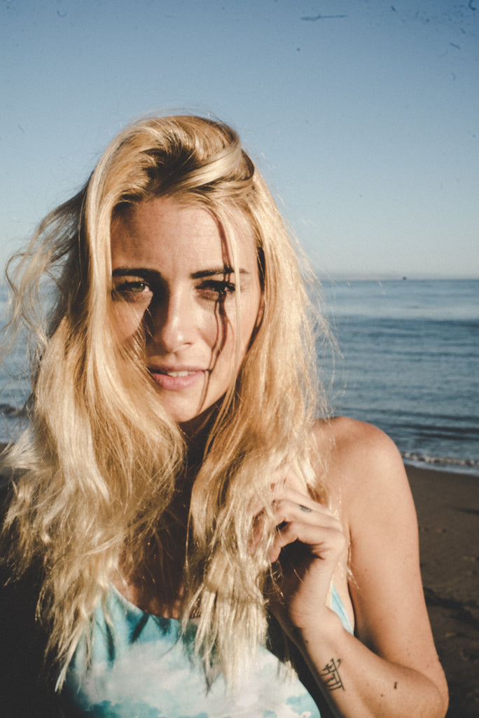 A close up of Alyssa with the ocean behind her and her hair in beachy waves