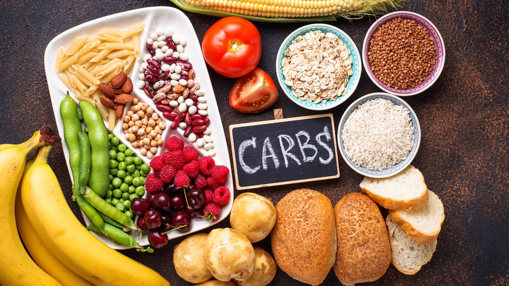 Carbs on chalkboard with high carbohydrate foods on table