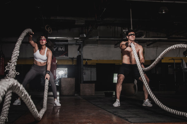 Two people working out with battle ropes for which you need lots of energy, and incorporating unprocessed foods into an athlete’s diet can ensure the proper amounts of it. 