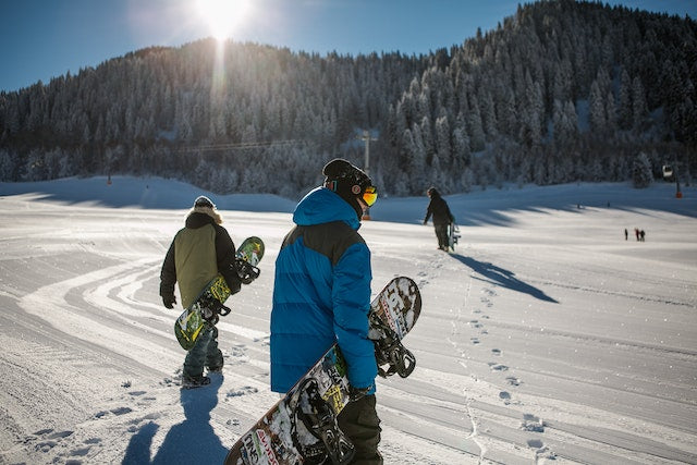 Snowboarders walking in the snow.