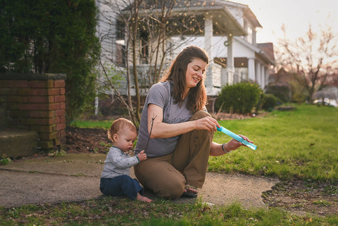 Aubrey with baby bud, blowing bubbles in the yard