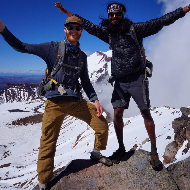 Two people rejoicing at the top of a summit in New Zealand while wearing Bedrock adventure sandals