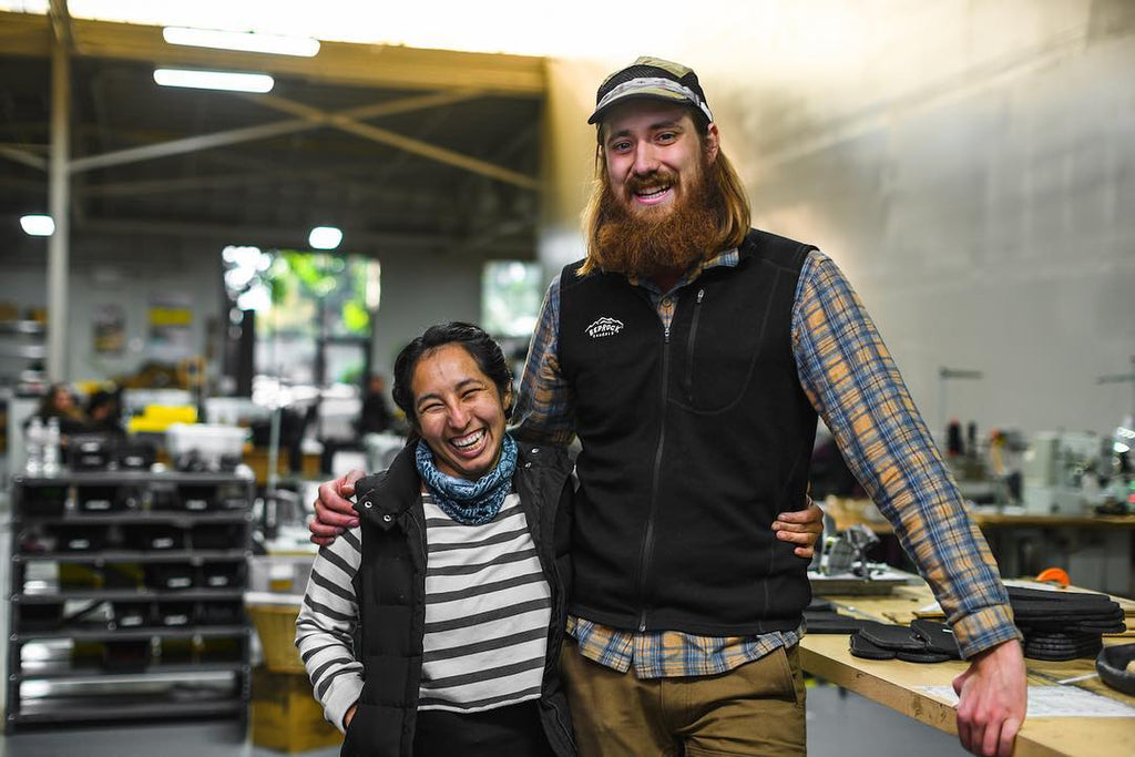 Two people smiling in old Bedrock Sandals headquarters