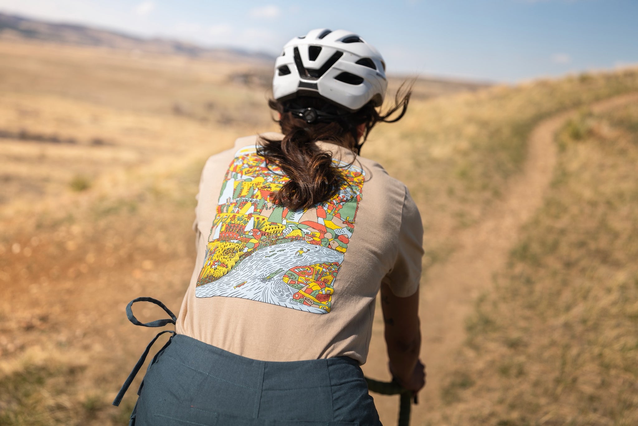 Bedrock MTN T Shirt in Mushroom Tan on person riding bike