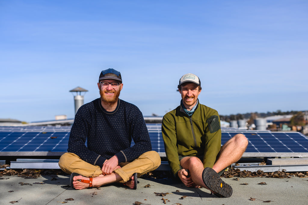 Founders of Bedrock Sandals sitting on roof by solar panels
