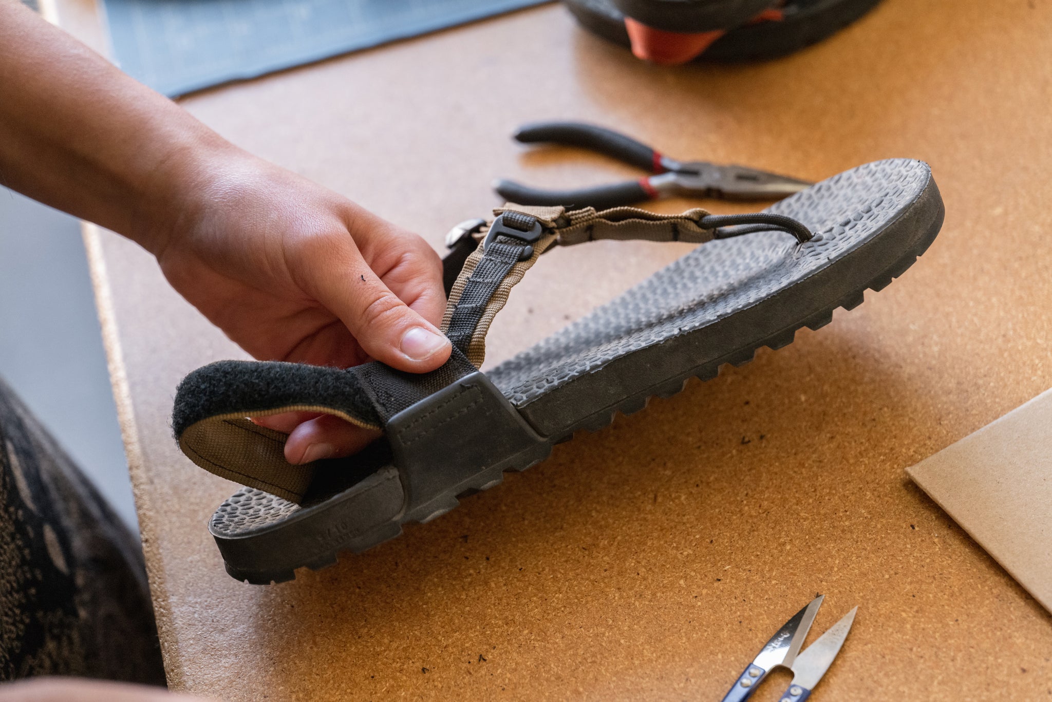 Beginning of heel re-strap process on pair of coyote tan sandals