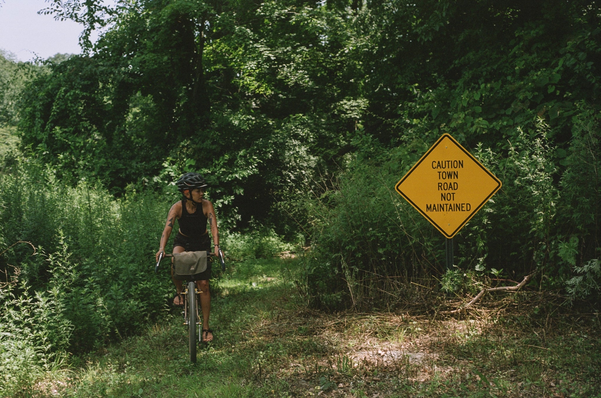 A person riding their bike through a grassy trail wearing Bedrock Sandals