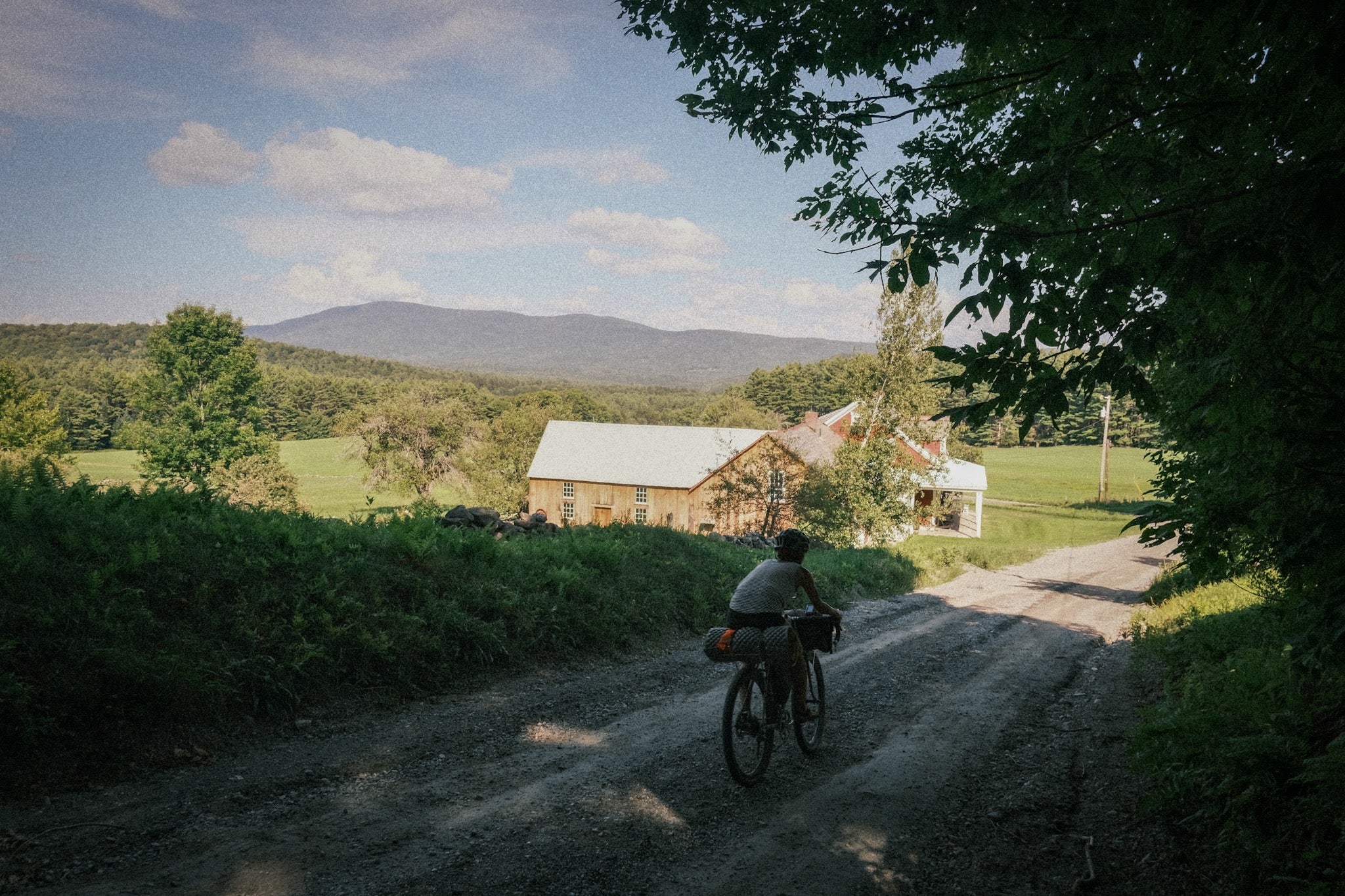 A person riding through the New England countryside wearing adventure sandals passing a barn along a dirt road