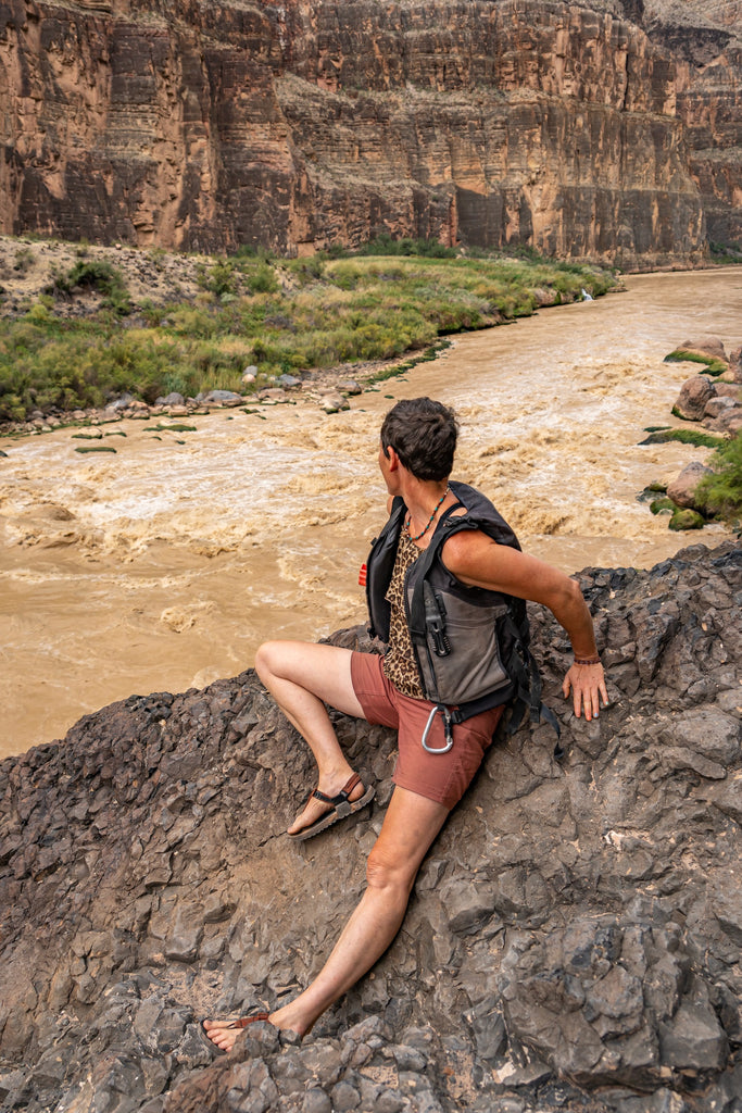 Person sitting on rock overlooking rapids on Colorado River