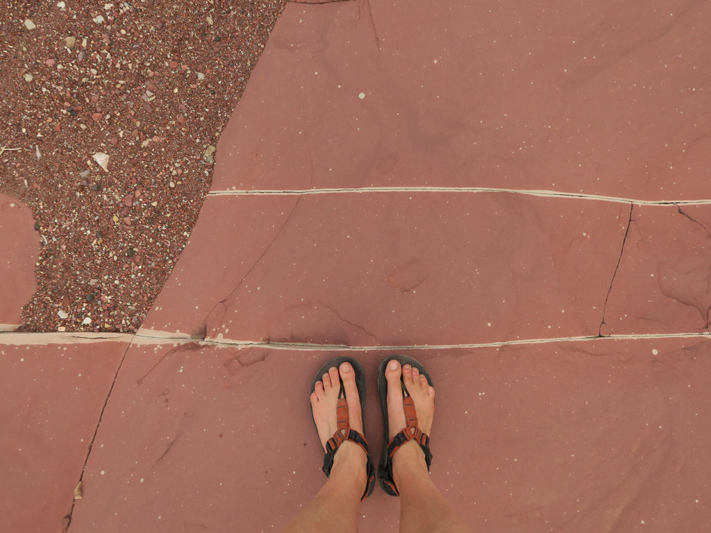 POV perspective looking at Bedrock Sandals on red rock