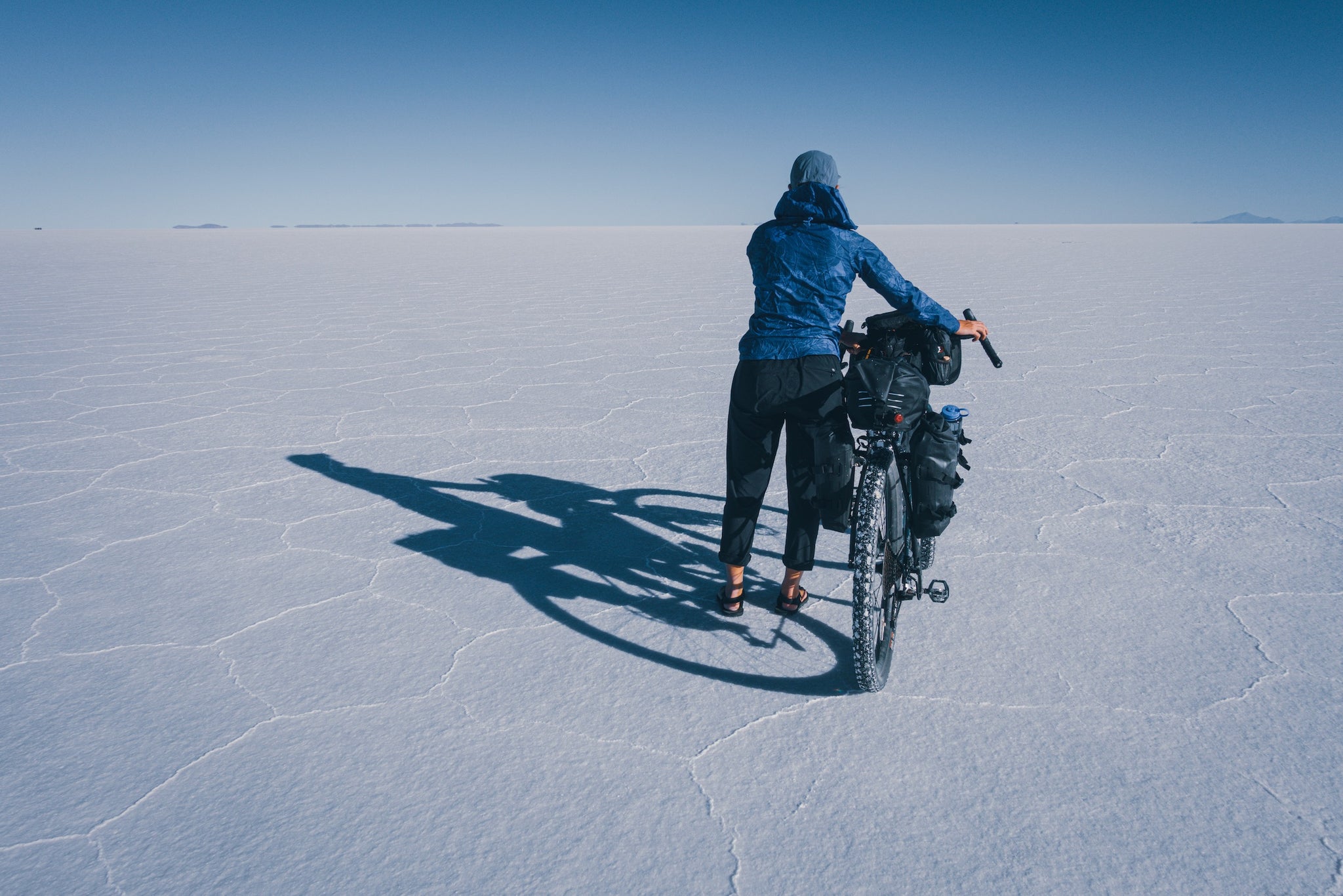 Bicyclist standing on salt flat with bike