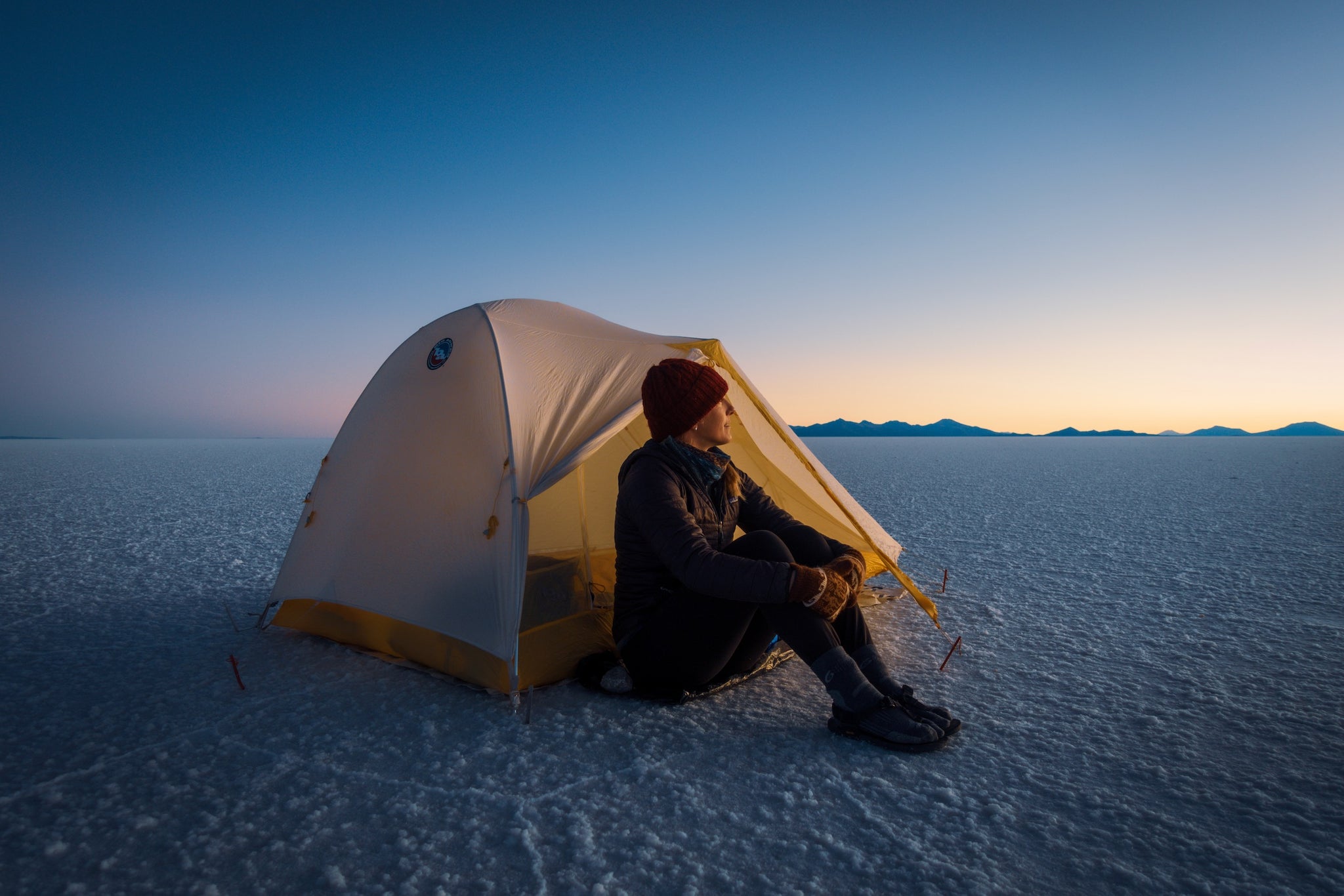 Bicyclist camping in tent on salt flat