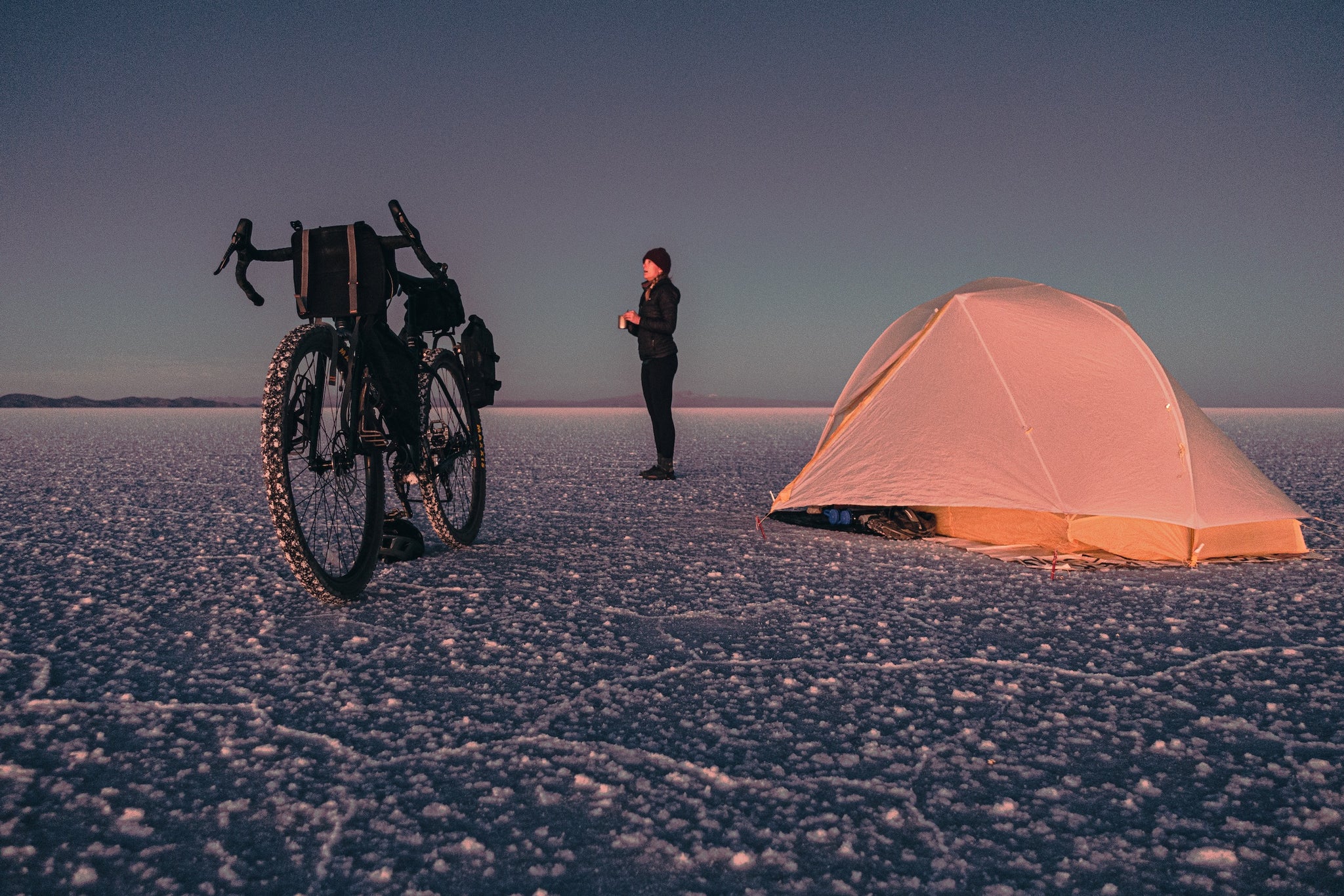 Bicyclist camping on salt flat with bike and tent