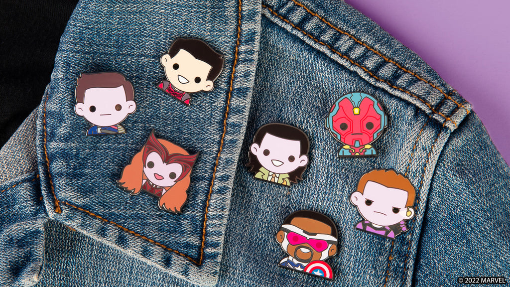 enamel pin collection featuring emojis from Hawkeye, WandaVision, Loki, and more pictured on a jean jacket