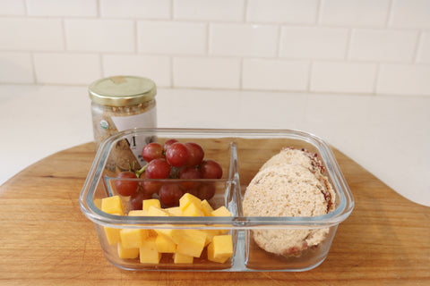 Tupperware filled with grapes, cheese and bread