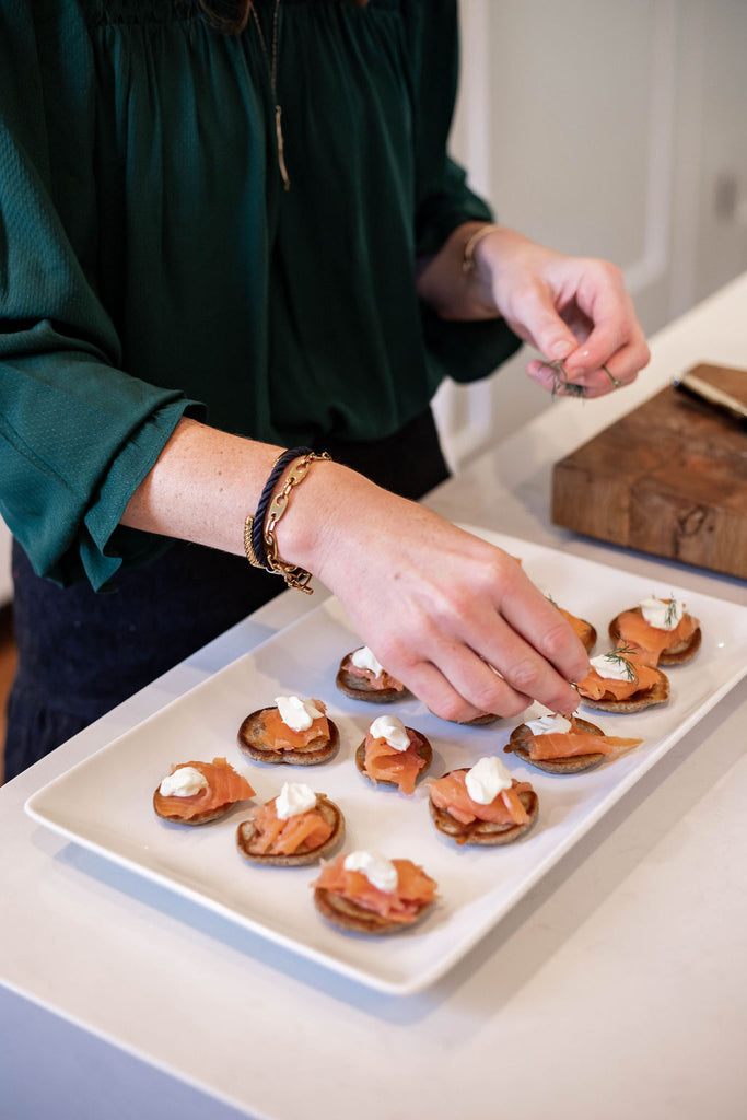 making smoked salmon blinis wearing nautical sailor stack of bracelets and coral branch bracelet and necklace 