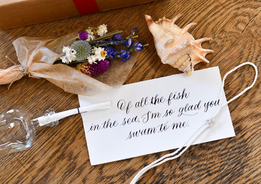 message in a bottle calligraphy note with dried flower bouquet, rope bracelet, and seashell