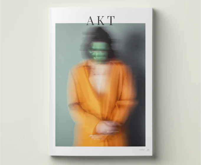 cover of issue 4 of AKT magazine - artfully blurry image of a person with a scary green face wearing a long orange coat