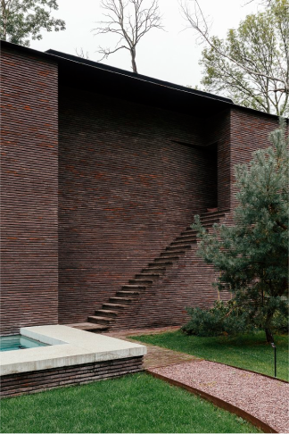 Another view of the residence - brick walls at different planes, with a brick walk and low white-topped brick wall