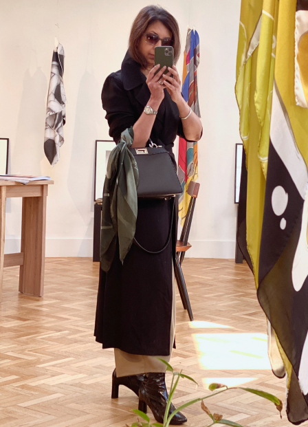 A woman photographing herself in the mirror, phone partially blocking her face - she is wearing an art scarf of a Man Ray Ray-o-graph, Coat - Stella McCarthy, Trousers - Cordera, Boots - Clergerie and standing next to a gently hanging large silk scarf