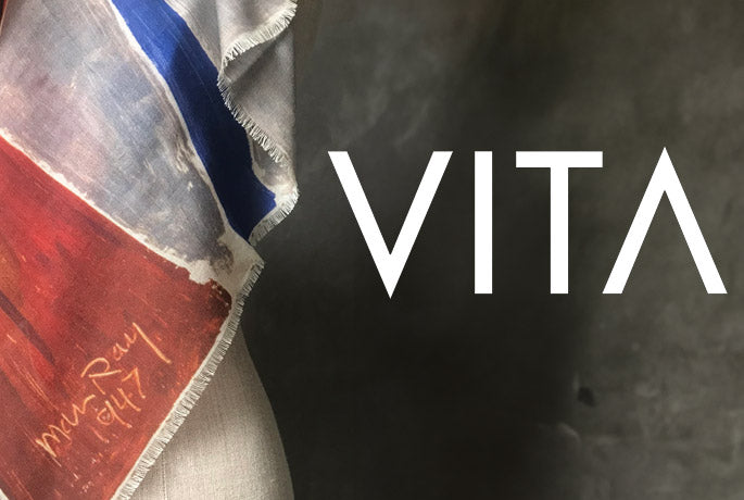 The Vita text logo in white on a chalkboard like background with a dress form partly in view on the left - it is draped with an Alba Amicorum scarf and you can see the signature of Man Ray. The shawl is  Man Ray IV (AFTER NON-ABSTRACTION 1947)