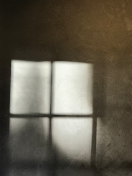photograph of panes of light coming through a window illuminating a textured wall